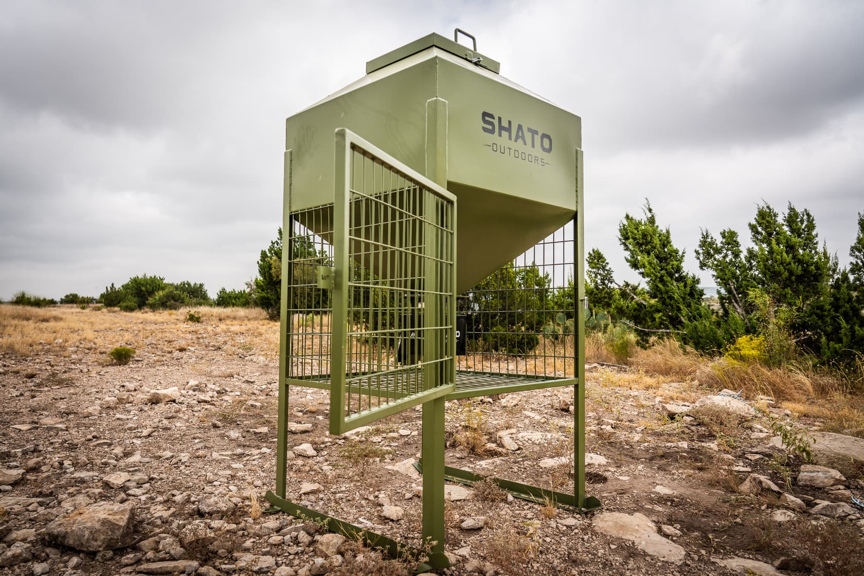 The feeder with its wire cage door swung open, showing the space under the hopper and the control box inside.